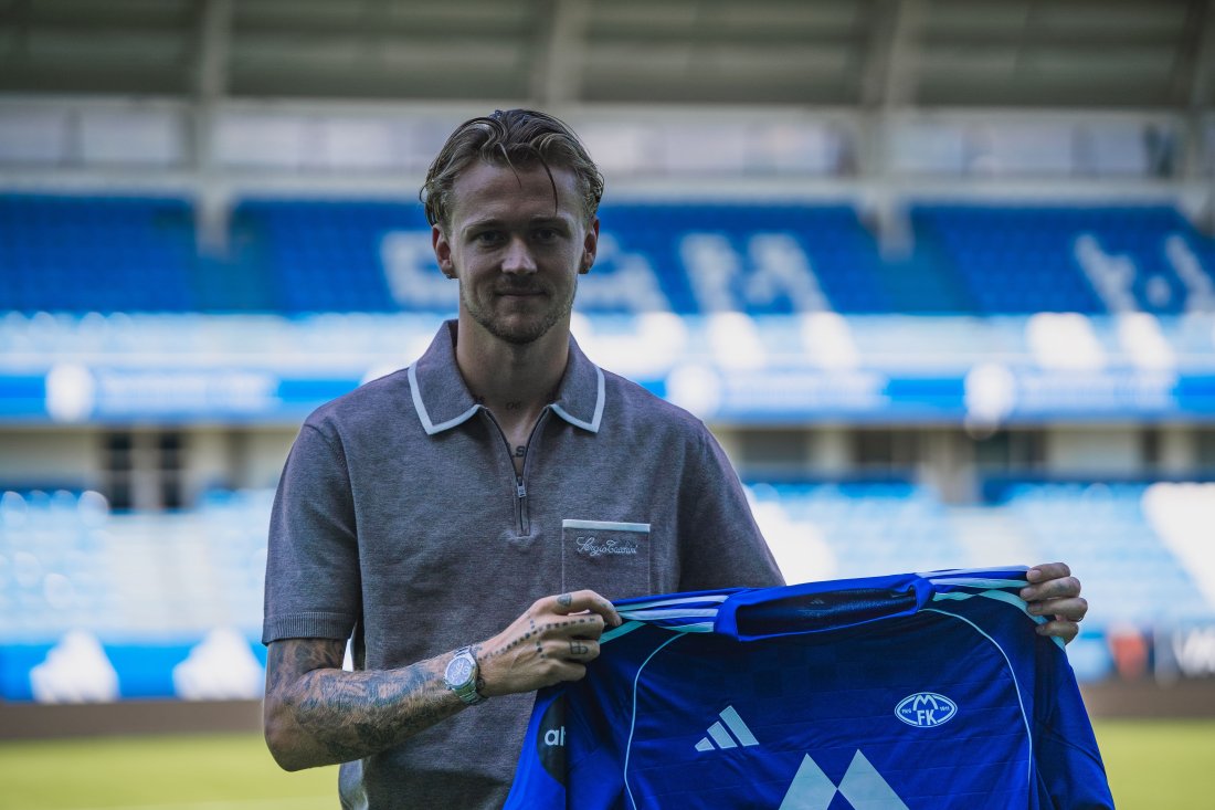 Birk Risa smiler og holder opp Molde Fotballklubbs blå hjemmedrakt inne på Aker Stadion, etter å ha signert for klubben sommeren 2025.